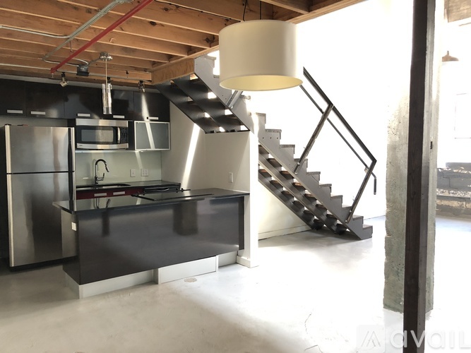 A modern kitchen with a stainless steel refrigerator and a stainless steel staircase.