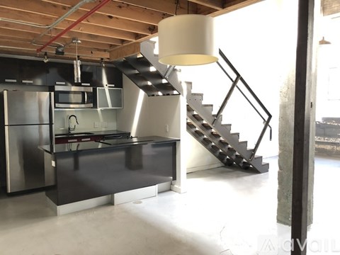 A modern kitchen with a stainless steel refrigerator and a stainless steel staircase.