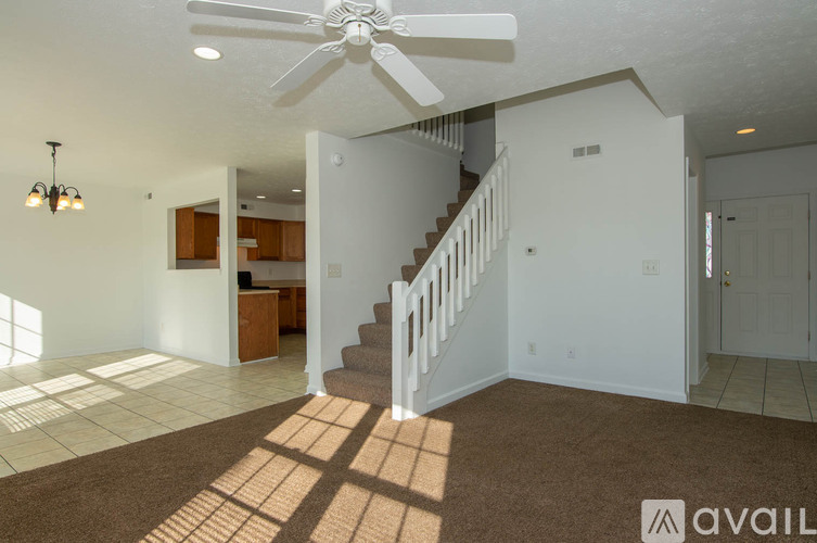 A living room with a staircase and a fan.