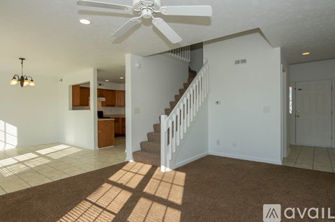 A living room with a staircase and a fan.