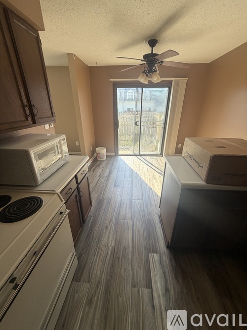 A kitchen with a fan on the ceiling and a window with a view of a fence.