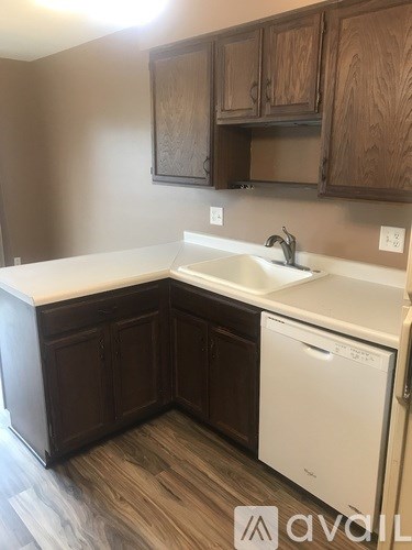 A kitchen with brown cabinets and a white dishwasher.