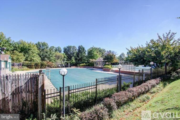 A pool surrounded by a fence and greenery.