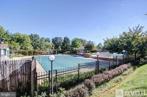A pool surrounded by a fence and greenery.