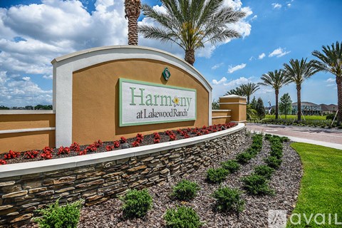 A sign that says Harmony at Lakemont Ranch is in front of some palm trees.