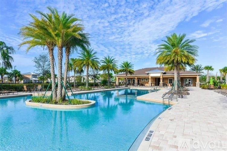 A large swimming pool surrounded by palm trees and a building in the background.