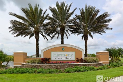 A sign for Harmony at Lakewood Ranch is surrounded by palm trees.