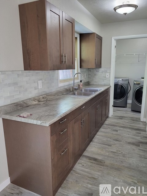 A kitchen with brown cabinets and a marble countertop.