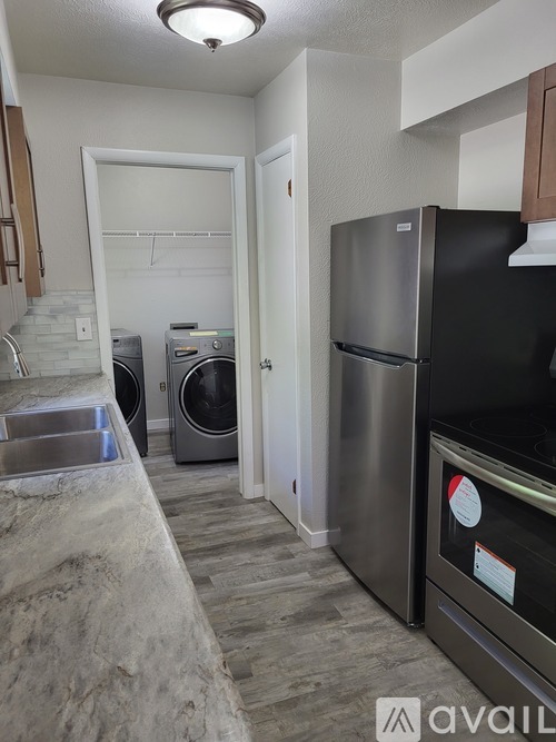 A kitchen with a black fridge and a washing machine.