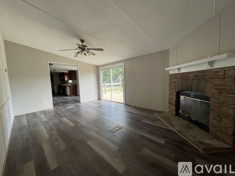A living room with a fireplace and a ceiling fan.