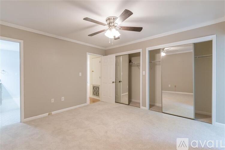 A spacious room with a ceiling fan and a door leading to a bathroom.