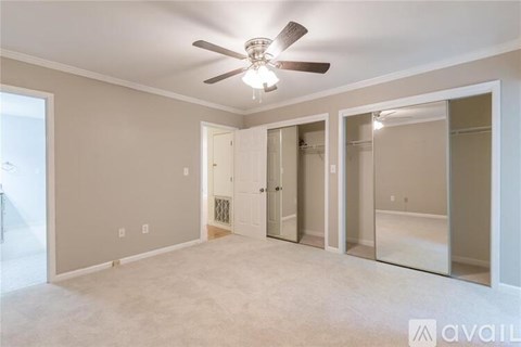 A spacious room with a ceiling fan and a door leading to a bathroom.