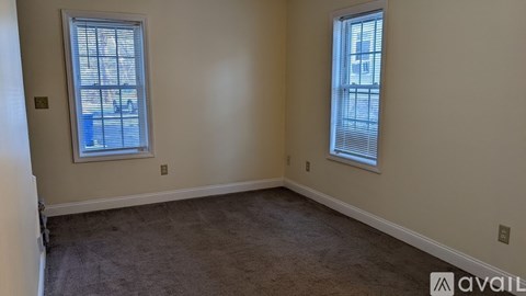 A room with two windows and carpeted floor.