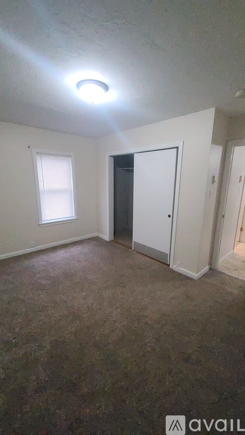 A room with a carpeted floor and a door leading to another room.