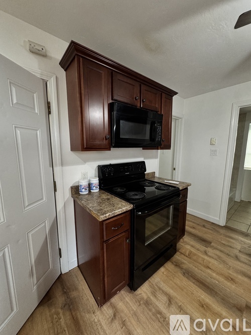 A kitchen with dark wood cabinets and a black stove top oven.