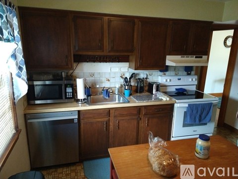 A kitchen with wooden cabinets and a stainless steel dishwasher.