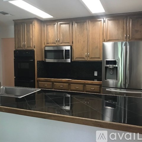 A kitchen with wooden cabinets and a stainless steel refrigerator.