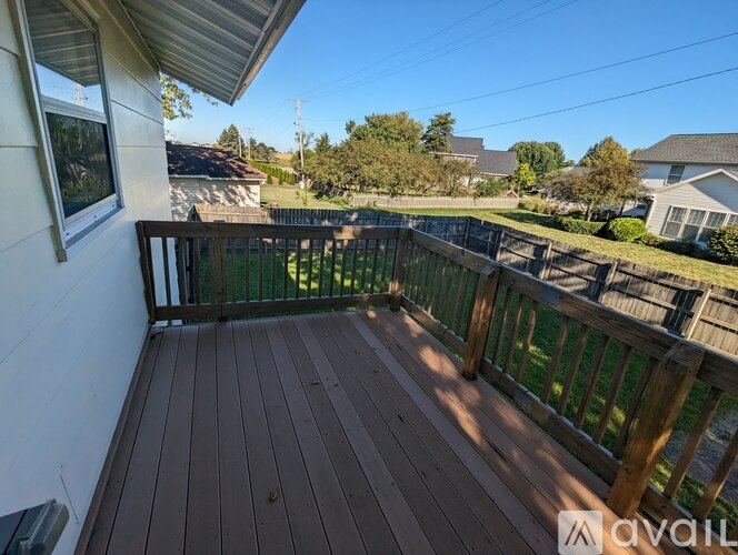 A wooden deck with a railing and a window overlooking a grassy area.