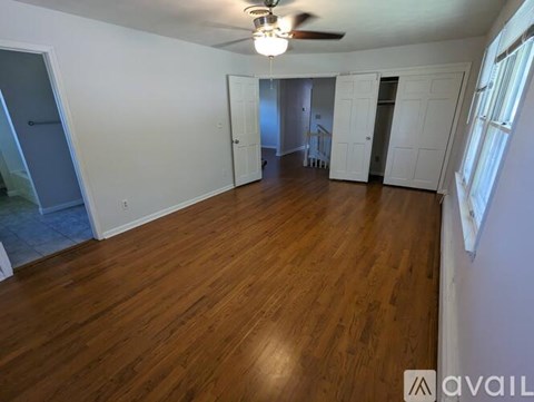 A spacious room with wooden floors and white walls.