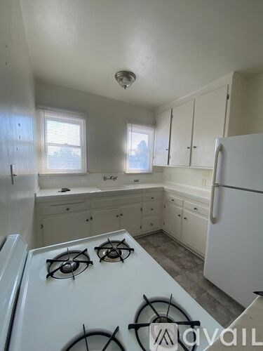 A kitchen with a white stove top and cabinets.