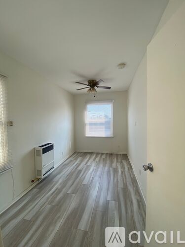 A room with a ceiling fan and a window with blinds.