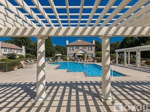 A pool surrounded by a white pergola.