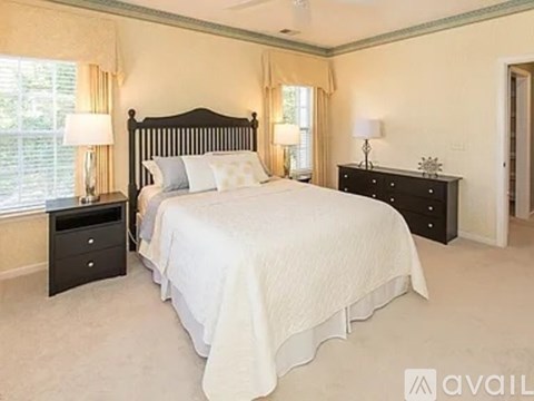 A bedroom with a large bed, two nightstands, and a window with curtains.