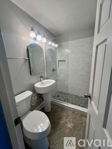 A bathroom with a toilet, sink, and mirror.