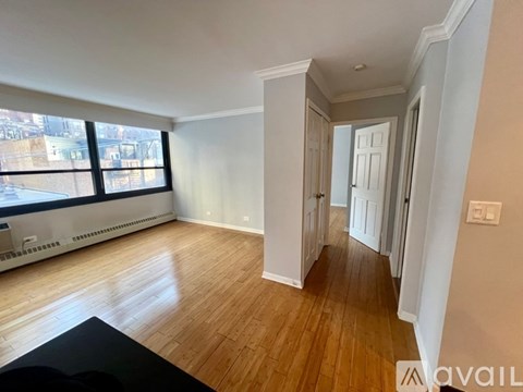 A room with wooden floors and white walls, with a window on the left side.