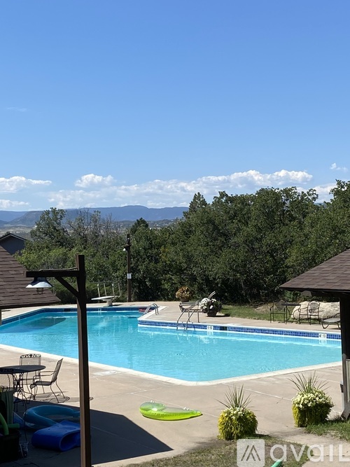 A pool with a table and chairs and a mountain in the background.