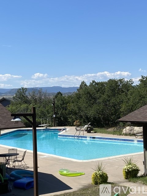A pool with a table and chairs and a mountain in the background.