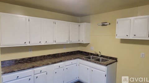A kitchen with white cabinets and a granite countertop.