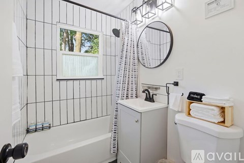 A bathroom with a white tub, a white sink, and a window with a view of trees.