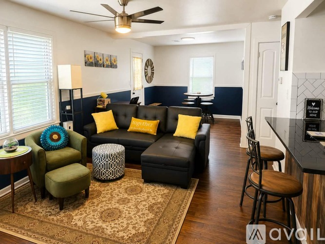 A living room with a black couch and yellow pillows.