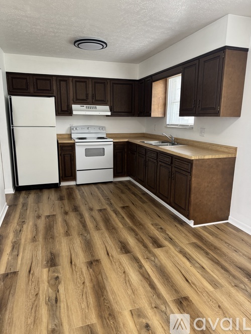 A kitchen with wooden floors and white appliances.