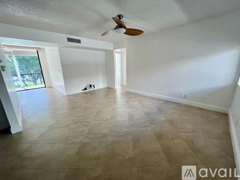 A spacious room with a ceiling fan and light switches on the wall.