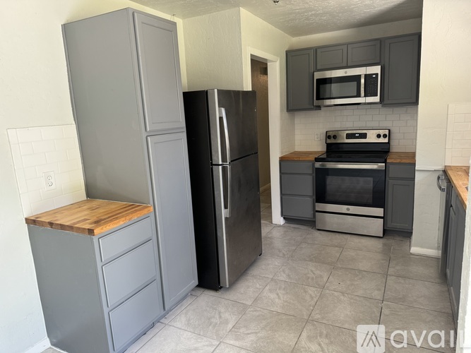 A kitchen with a refrigerator, oven, and microwave.