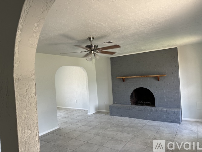 A room with a fireplace and a fan on the ceiling.