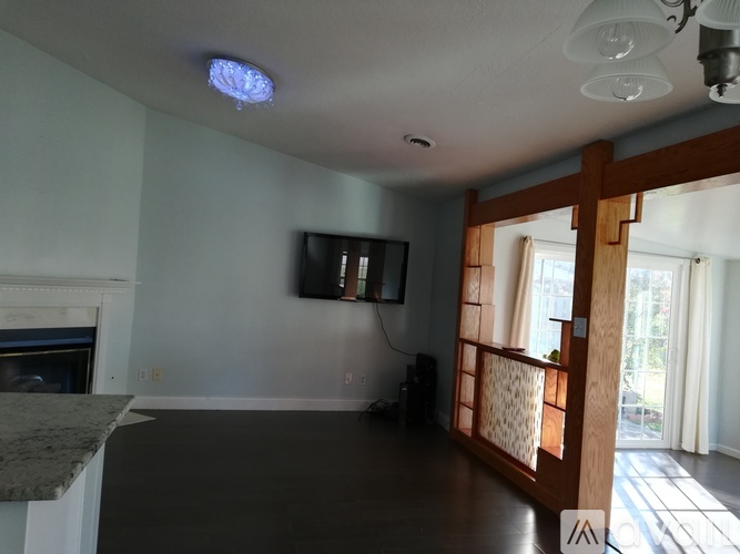 A living room with a fireplace and a flat screen TV mounted on the wall.
