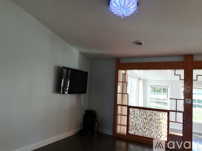 A room with a television and a window with a wooden frame.