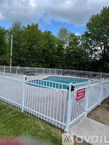 A pool surrounded by a white fence with a sign on it.