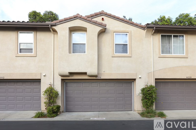 A beige house with three garages and a balcony on the second floor.