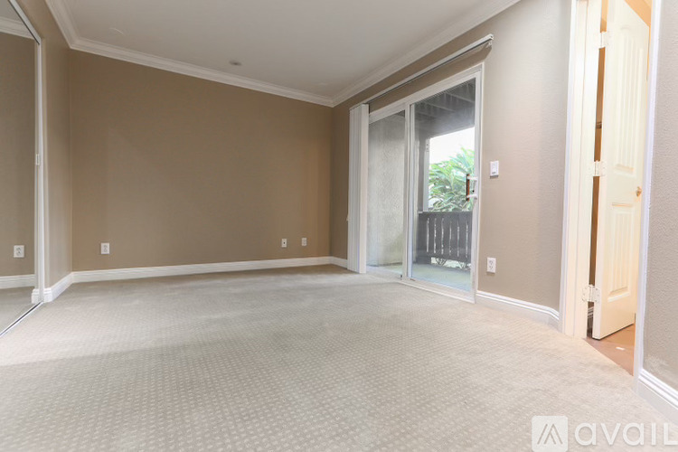 A spacious room with beige walls and carpeted floor.