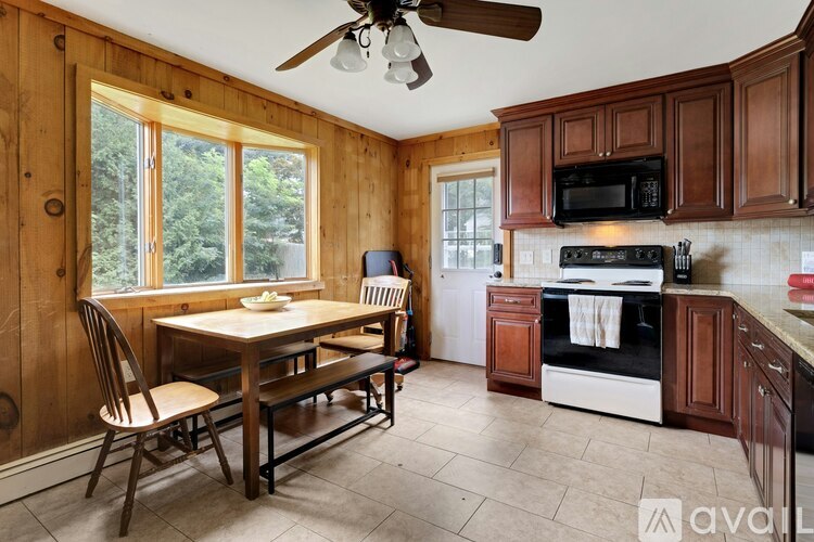 A kitchen with wooden cabinets and a black microwave above the stove.