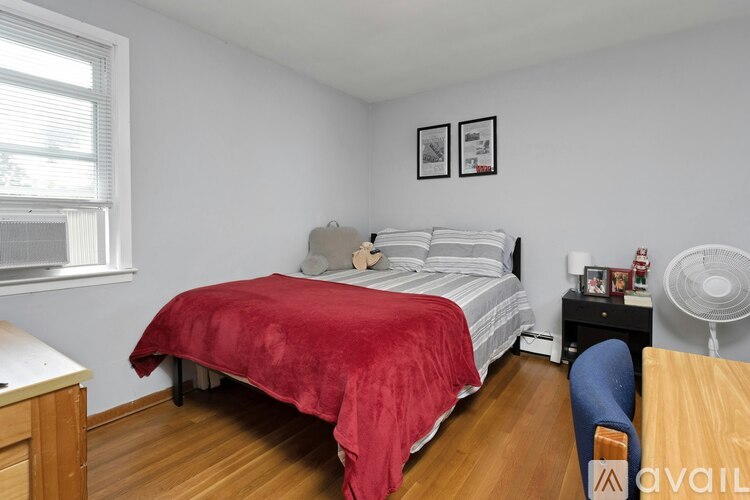 A bedroom with a red bedspread and a white bed.