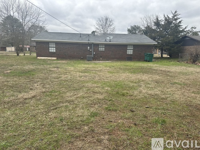 A small brick building with a green dumpster in front of it.