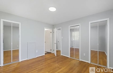 A room with wooden floors and white walls, with a large mirror on the wall.