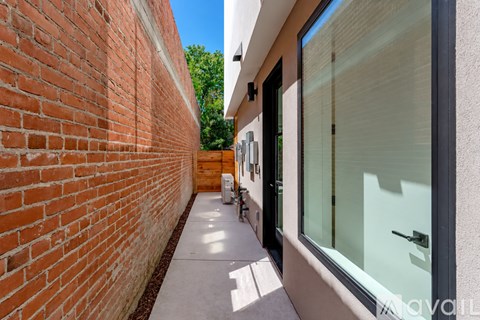 A narrow alley with a brick wall on one side and a glass door on the other.