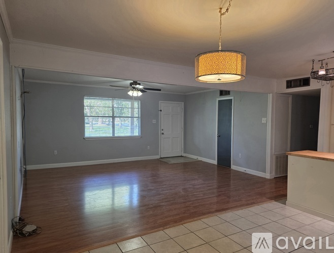 A room with wooden floors and a hanging light fixture.