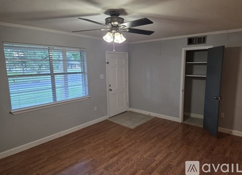 A room with a ceiling fan and a window with blinds.